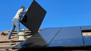 Ein Mann montiert Sonnenkollektoren auf ein Dach © Foto von Bill Mead auf Unsplash